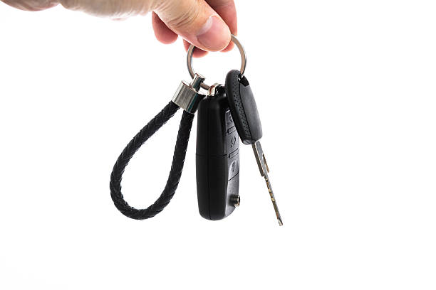 Human hand holding car keys on white background