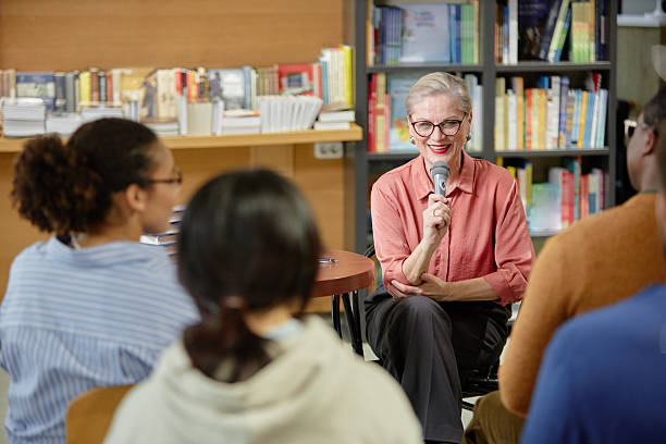 Senior Caucasian Woman Speaking into Microphone Addressing Diverse Audience
