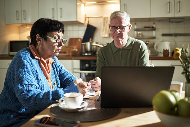 Elderly Caucasian Couple Using Laptop in Kitchen