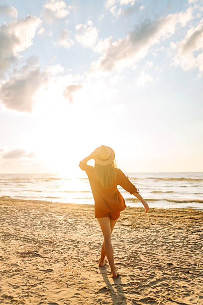 istock Young woman walking on the beach at sunset. 2221888119