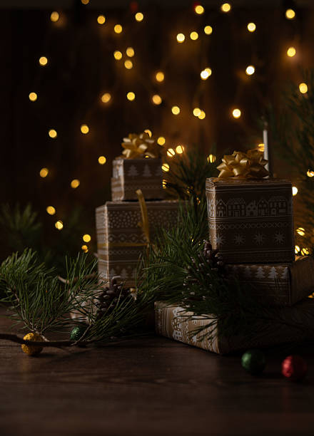 istock Beautifully Wrapped Gift Boxes with Festive Decor Surrounded by Pine Branches and Pinecones in a Warm Ambience with Twinkling Lights for Seasonal Celebration 2221888302