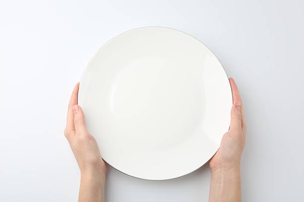 istock Woman with empty ceramic plate on white background, top view 2221888661