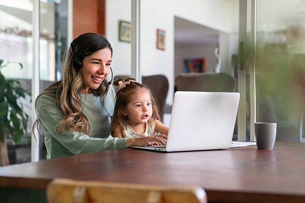 istock Mother working at home and talking on a video call while caring for her daughter 2221889498