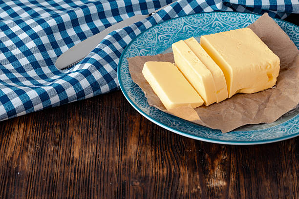 Cut butter on plate with blue towel on kitchen table. close up.