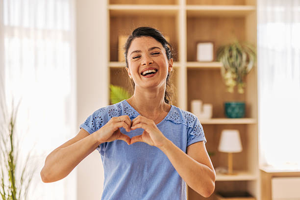 istock Happy woman making heart shape with hands at home 2221892013