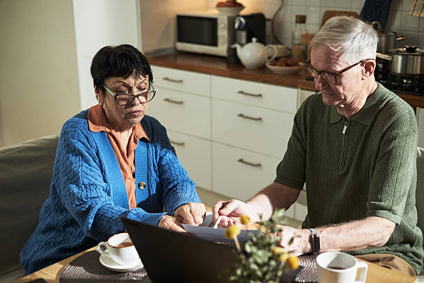 istock Senior Couple Reviewing Utility Bills on Kitchen Table 2221892863