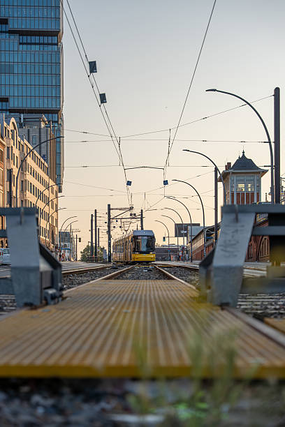 A yellow Berlin tram approaches on straight tracks in the soft evening light.