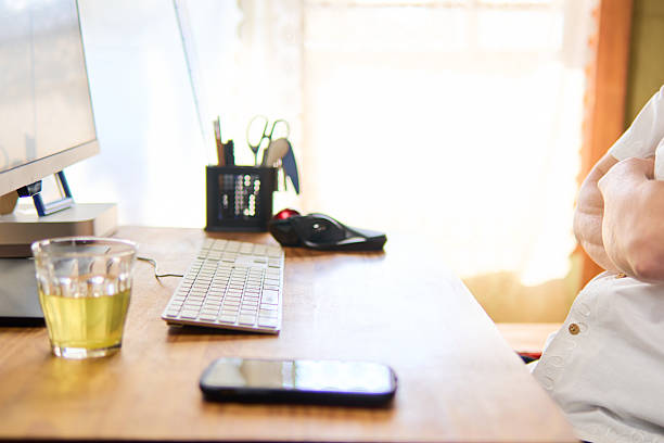 A man in his 50s is staring intently at his computer screen with his arms folded, deep in thought.