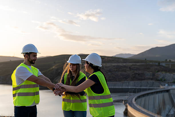 istock Engineers joining hands near dam at sunset: teamwork and collaboration in renewable energy 2221908595