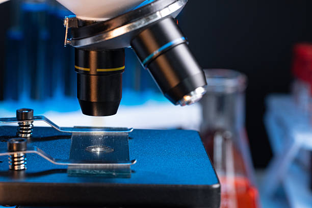 istock Microscope with lenses close up against dark background 2221910875
