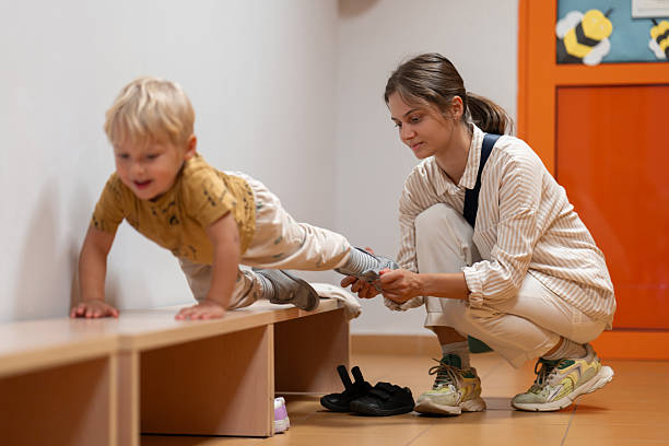 Mother Helping Child Get Ready in Kindergarten Cloakroom
