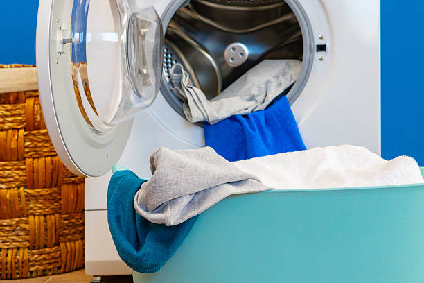 istock Washing machine with laundry on blue wall background 2221914835