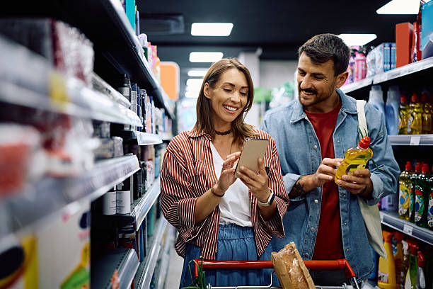istock Happy couple using smart phone while buying in a supermarket. 2221916718