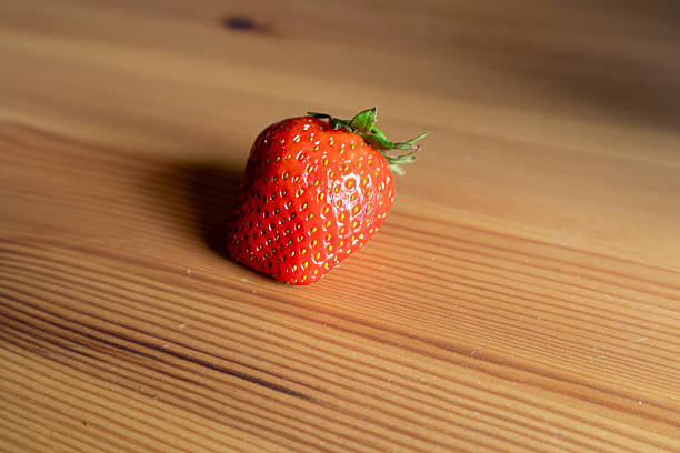 Single Ripe Strawberry on Rustic Wooden Table. Natural Organic Fruit