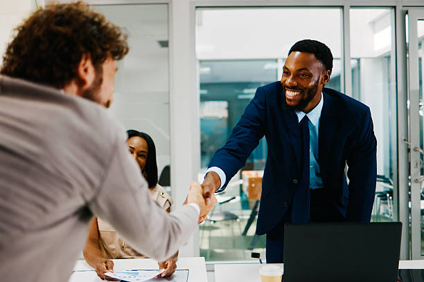 istock Two businessmen shaking hands over a desk in a modern office 2221927314