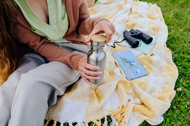 istock Hands opening thermos on picnic blanket with journal and binoculars 2221929353