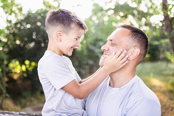 Happy young boy sitting on his dad's shoulders at home