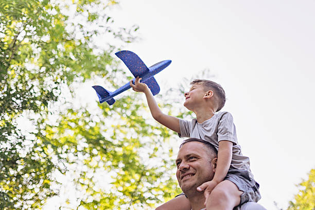 istock Father and Son Playing with Toy Airplane in a Sunny Park 2221933098