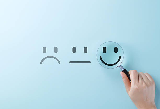 istock Customer feedback and Satisfaction survey concept. A hand holding magnifying glass focus on a smile face amidst different emotions, customer review, satisfaction feedback, and service improvement. 2221935127