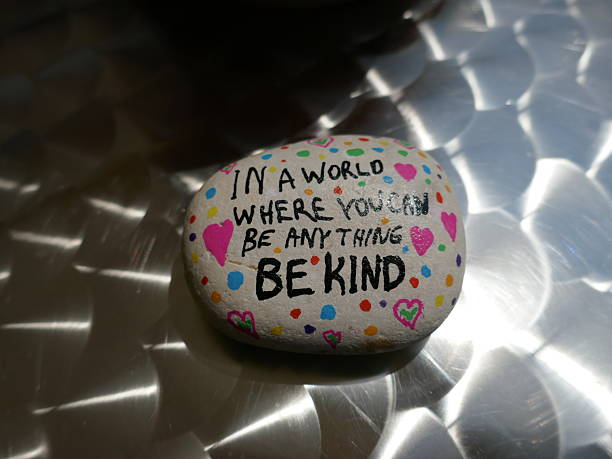 istock Shiny metal patterned surface with be kind kindness rock and sun reflection 2221938297