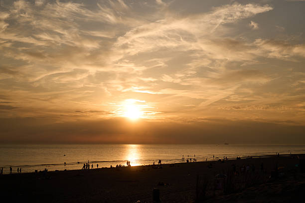 People relaxing on the beach during a beautiful golden sunset over the ocean