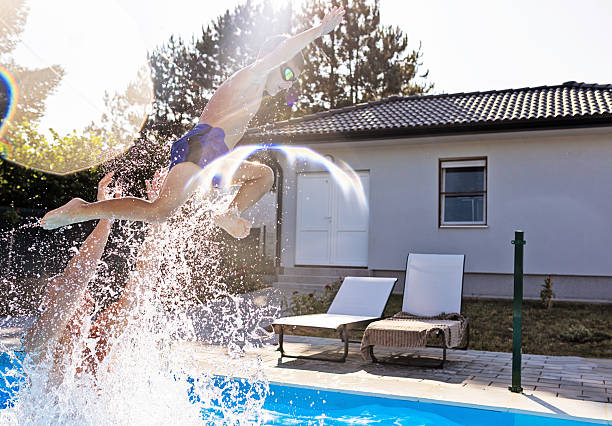 istock Father Tossing Son Into Backyard Swimming Pool on a Clear Summer Day 2221941488