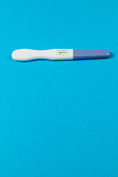 Close-up of female hand holding a pregnancy test strip indoors, symbolizing personal health and decisions.