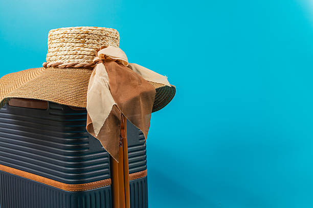 A stylish straw hat rests elegantly on a blue suitcase, accompanied by a soft ribbon. Perfect for summer adventures and getaway planning.
