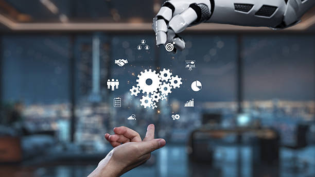 istock Robotic Hand Reaching Towards Human Hand with Digital Icons Representing Technology, Business, and Innovation in Modern Office Setting. Auvana 2221966330