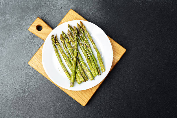 istock Grilled asparagus served on a white plate on a wooden cutting board 2221966933