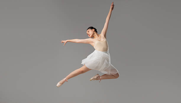 istock Ballet Dancer in Mid-Air: Graceful leap Light-toned leotard and white skirt Studio setting Elegant form 2221978013