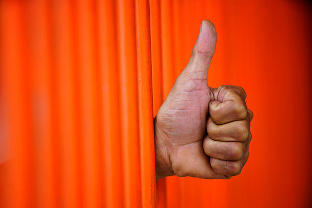 istock Hand Giving Thumbs Up Gesture Behind Vertical Orange Bars 2221984762