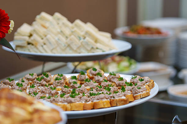 Close-up of tuna bruschetta garnished with parsley and stacked white bread sandwiches displayed on a buffet table at a catered event.