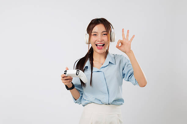 istock Game session with cheerful woman, headphones on, giving ok gesture while holding controller 2221990193