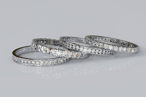 istock Four eternity rings with tiny diamonds laying on white glossy background 2222001688
