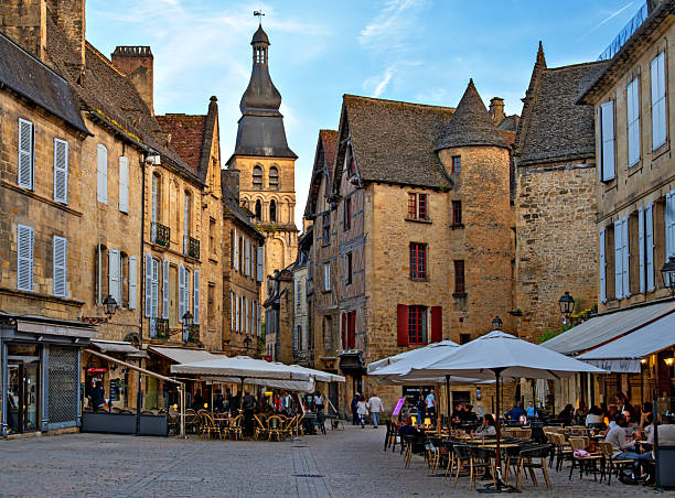 sarlat-la-caneda, france - may 24, 2025: place de liberte with outdoor restaurants in the light of the setting sun