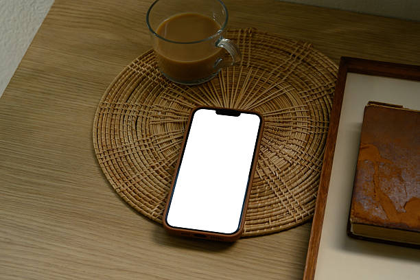 istock Smartphone with blank screen on wooden table next to coffee and vintage book 2222006908