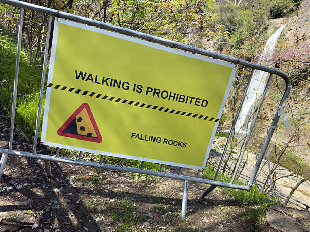 istock Warning sign by scenic waterfall trail alerts about falling rocks and prohibits walking, combining natural beauty with strong safety message in mountainous area 2222007598