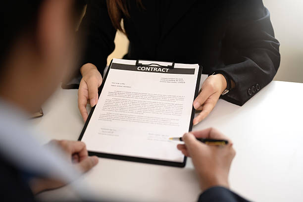 istock Man completing contract signature while businesswoman assists with document presentation 2222007880