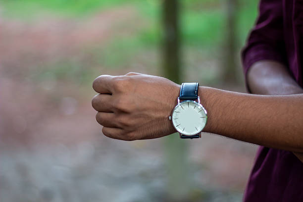 A human wears a watch on his hand, and the background is blurred behind them