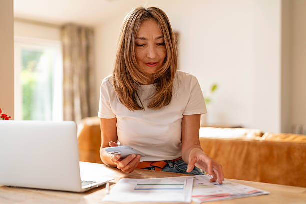 istock Woman using a smartphone while organizing documents in a bright, cozy home office during the daytime 2222011723