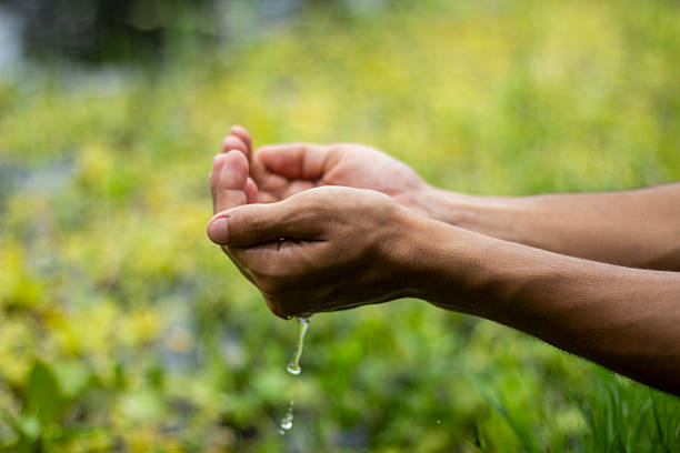 istock A fair-skinned boy is playing with water on his hands. Lifting water with both hands, and some of the water is flowing 2222011878