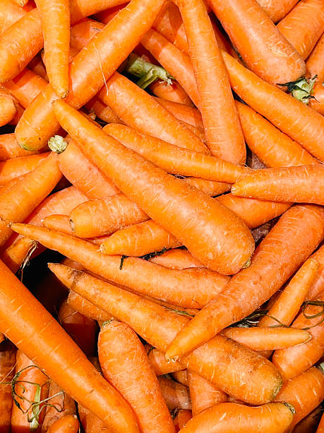 A full-frame close-up shot of a pile of vibrant orange carrots.