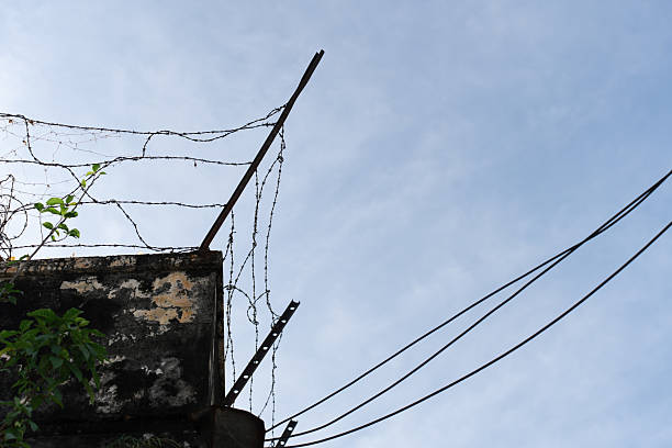 istock Barbed wire installed along the top of a concrete wall. 2222016422