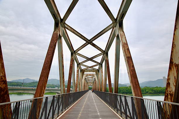 Yangpyeong County, South Korea - May 19th 2025: A closer view inside the Bukhangang Railroad Bridge shows crisscrossing steel trusses weathered by age, now framing a peaceful bike route above the river.