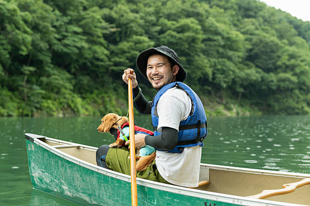 A man enjoying kayaking down a river with his dog