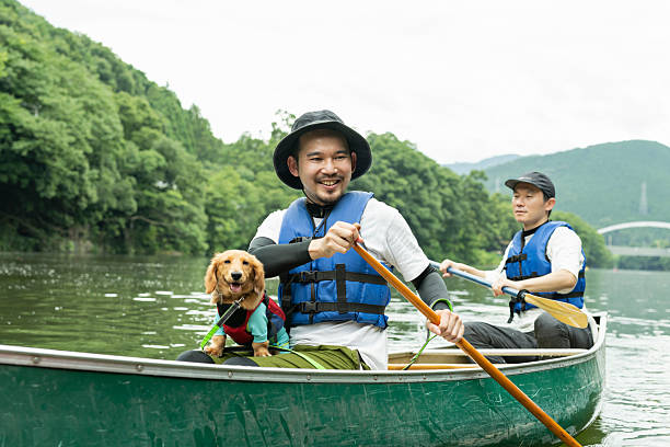 A man enjoying kayaking down a river with his dog and friends