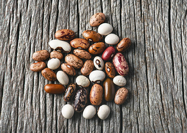 Top view of colorful mix dried legume beans (Phaseolus vulgaris) on rustic wooden background.
