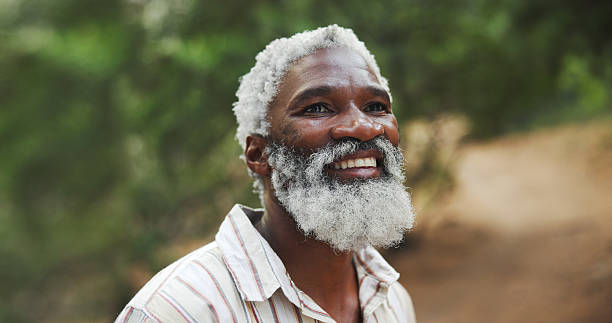 Hiking, thinking and old man with smile, travel and thoughtful with reflection, explore and countryside. African person, outdoor and hiker with break, nature and woods with retirement and trekking