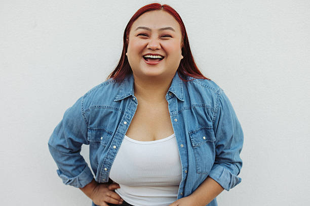 istock Confident woman smiling in casual denim jacket against a plain white wall 2222025186
